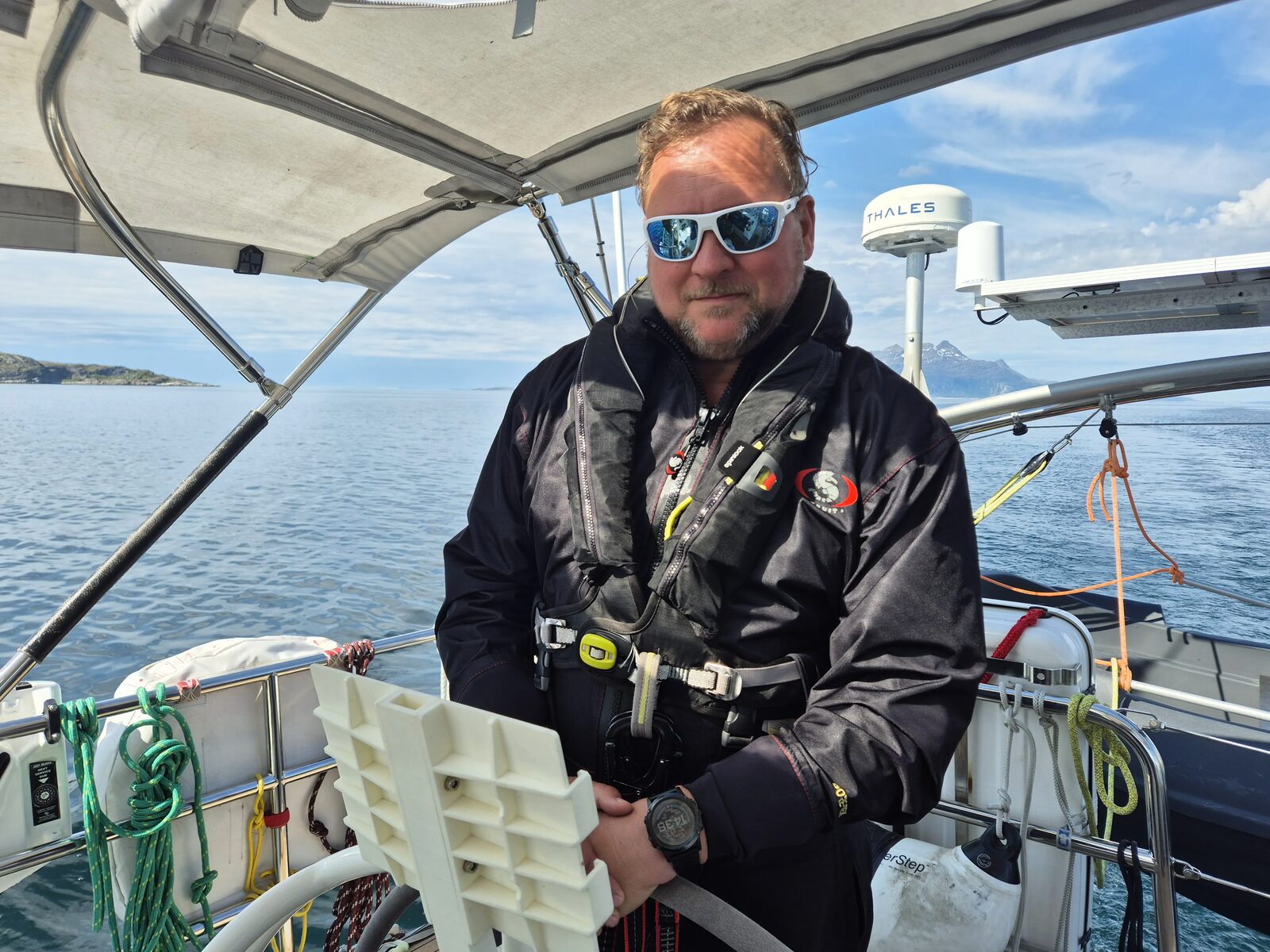Skipper mit Rettungsweste am Ruder vor der norwegischen Küste